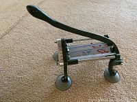 Side view of French fry cutter showing long black lever handle and suction cup feet on beige carpeted floor.