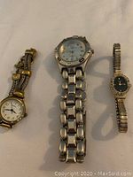 Photo of three wristwatches including Bulova, Fossil, and an unknown brand, showing different bracelet styles and dial faces.