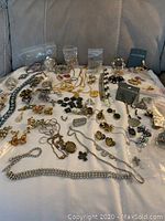 Full view of the assortment of necklaces, bracelets, earrings, and brooches spread out on a fabric surface.
