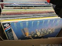 Side view of approximately 50 vintage LP records packed in cardboard box with the album 'Supertamp' facing forward.