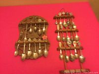 Photo of two wooden racks holding collector spoons against a red background.