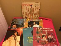 Six vintage Elvis Presley vinyl LP records arranged on a flat surface, showing cover art and titles including '50,000,000 Elvis Fans Can't Be Wrong' and 'Blue Christmas'