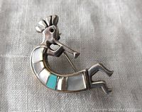 Front view of the Kokopelli sterling silver brooch pendant showing mother of pearl and turquoise inlaid design and flute player figure
