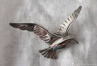Front view of a vintage sterling silver Beau brooch shaped as a bird in flight, showing detailed feather work and smooth polished silver surface.