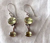 Front view of sterling silver earrings with two oval lemon quartz stones each, showing clear yellow facets and hook style ear wires.
