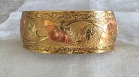 Close-up photo of gold wash brass and copper wash engraved floral and leaf design on bangle outer surface