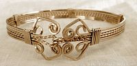 Full view of the bangle bracelet showing braided wire around the band and the ornate wire formed hook closure.
