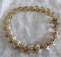 View of vintage gold wash 800 silver filigree heart shape bracelet laid flat showing linked heart-shaped decorative elements.