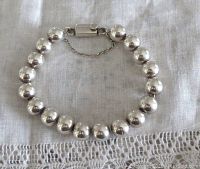 Bracelet laid flat showing round 10 mm beads and push-in clasp with safety chain.