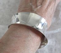 Concave sterling silver bangle worn on wrist showing fit and shape.