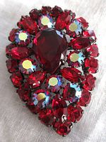 Front view of the brooch showing red tear drop, marquise, round, and AB stones in japanned setting.