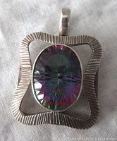 Front view of the pendant showing the textured silver frame and oval mystic topaz gemstone.