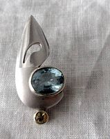 Front view of the silver modernist pendant with blue topaz and citrine stones on white textile background.