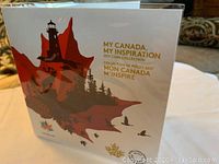Front cover of the commemorative coin collection folder showing artwork of a red maple leaf with a lighthouse and natural elements.