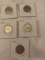 Obverse side of 5 Canadian quarters mounted in cardboard holders with handwritten dates 1941 to 1945.