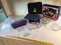Full view of collection showing Pyrex glass baking dishes of various sizes and shapes, some with lids, and boxed Pyrex portable electric skillet with black carrying bag.