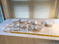 Overview of all baking and serving dishes laid out on table with measurement tape for scale