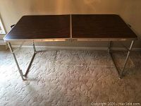 Full view of wood and aluminum lightweight folding table showing whole top and legs deployed.
