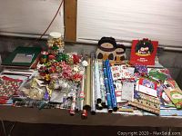 Overview of all items laid out on a table showing wrapping paper rolls, bags, bows, and tags in various Christmas patterns and colors.