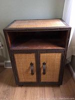 Front view of wooden cabinet with wicker overlay on doors and open cubby shelf above.