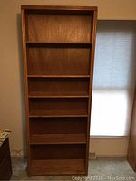 Full front view of tall oak bookcase showing all shelves