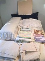 Photo showing various blankets, pillows, pillowcases and linens arranged on a surface
