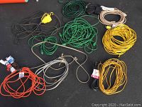 Top view of various colored extension cords laid out on black surface showing multiple lengths and colors.