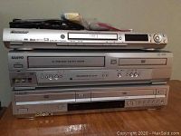 Front view of stacked Pioneer DVD player on top, Sanyo 4-head Hi-Fi VCR/DVD player in middle, and Sony DVD/VHS combo on bottom, showing model details and front AV inputs.