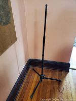 Full view of the black adjustable microphone stand with tripod base, upright position.
