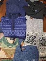 Six men's vintage sweaters in various colors and patterns laid out flat.
