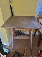 Front and side view of the square homemade wood work table showing its structure and surface condition.