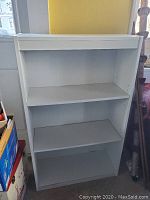 Front view of white 3-shelf wooden bookcase with minor wear.