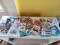 Assortment of loose baseball and football cards spread on table showing a variety of cards including team logos and player images.