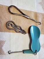 Three vintage metal tools for corset and shoe lacing on patterned cloth.