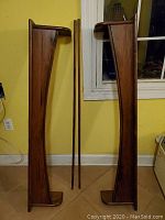 Set of two long vintage wooden valances and two wooden rods leaning against a yellow wall and window.