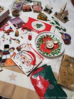 Photo showing an assortment of vintage Christmas ornaments and holiday decorations including stained glass pieces, miniature houses, holiday plates, and various small figurines.