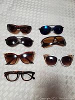 Top down view of six pairs of glasses arranged in two columns on a textured light-colored fabric surface.