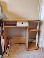 Front view of the desk showing the drawer, open shelves, and curved shelving unit on the right side.