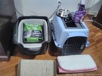Contains view of cat carrier, litter boxes, cat litter bag, cleaner bottle, and food dishes