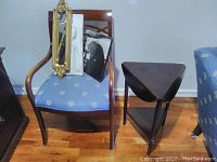 Photo showing the Kimball International wooden chair with blue cushion, the dark triangular side table, and the mirror leaning on chair.