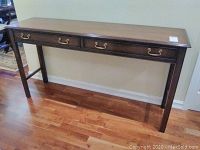 Front view of the wooden console table showing two drawers with brass handles and straight legs.