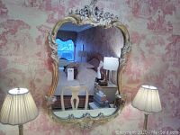 Full front view of mirror hung on wall against patterned wallpaper