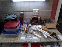 Wide view of all items on countertop showing thermoses, Tupperware, salad spinner, nested bowls, and utensils