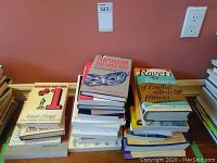 Stacks of self help and reference books including Looking Out For #1, Roget's Thesaurus, and Impostor Phenomenon CD Confidence Power Course