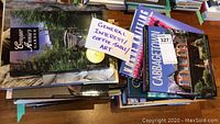 Photo showing a stack of multiple books with a handwritten note reading 'General Interest Coffee Table Art'. Visible titles include 'Cougar Annie's Garden' and 'Cabbagetown'.