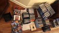 Multiple stacks of assorted music CDs arranged on the floor, showing a variety of genres and artists.