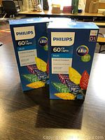 Two boxes of Philips 60 multi-color LED C6 indoor/outdoor string lights placed on a table, showing packaging and product details.