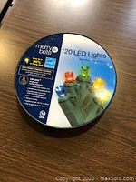 Photo of round container showing labeling of MerryBrite 120 LED multi-color lights with info about energy efficiency and usage.