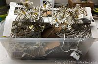 3 vintage Italian-made string light strands with white twisted cords, yellow bulbs, and white plastic snowflake covers, stored in a plastic container