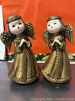 Photo shows two vintage angel music box figurines, each about 8 inches tall, with golden dresses and wings, standing side by side.